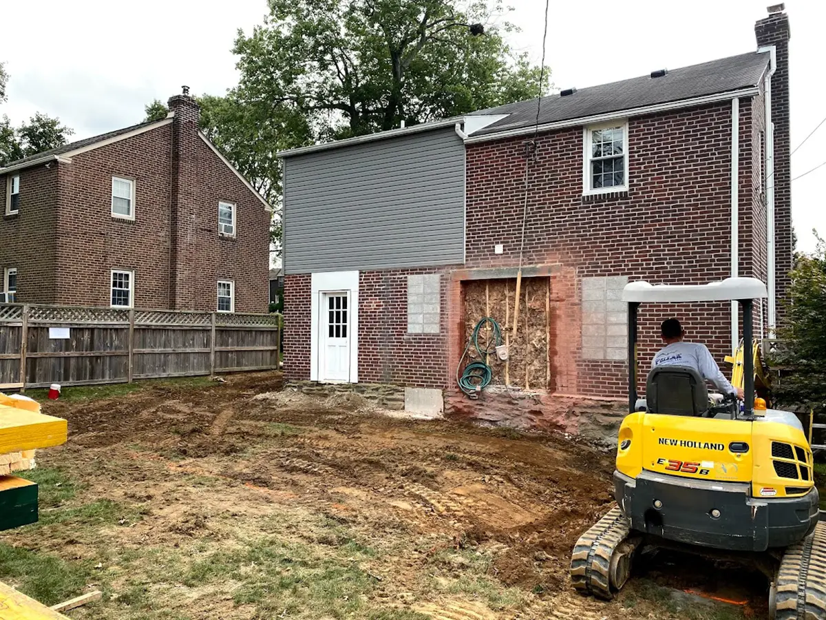 A brick home and a man operating heavy machinery