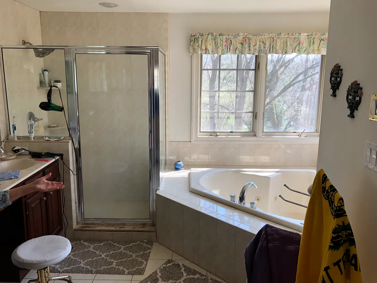 A dated bathroom with shower, jacuzzi, and an old vanity