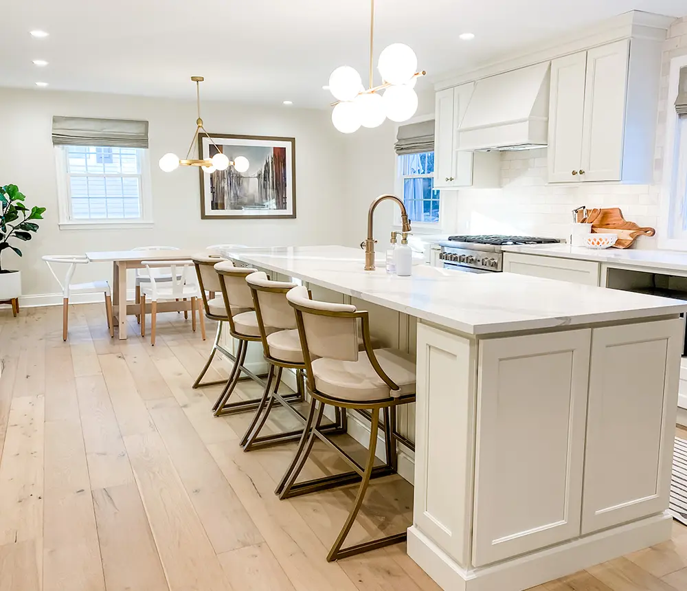 Quartz countertops, golden fixtures, and unfinished wood flooring in a kitchen