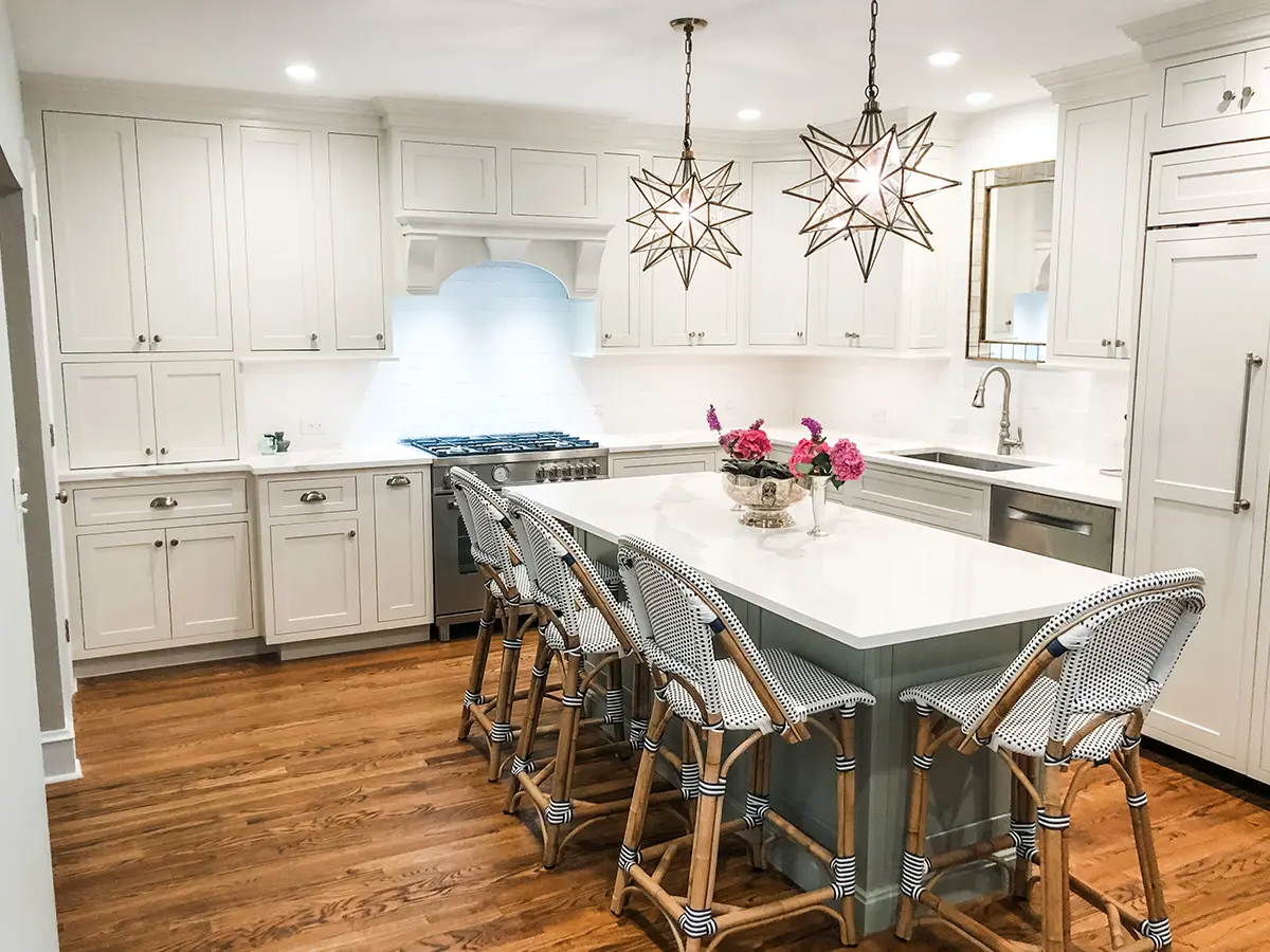 A beautiful kitchen with wood floors, quartz countertops, and white cabients