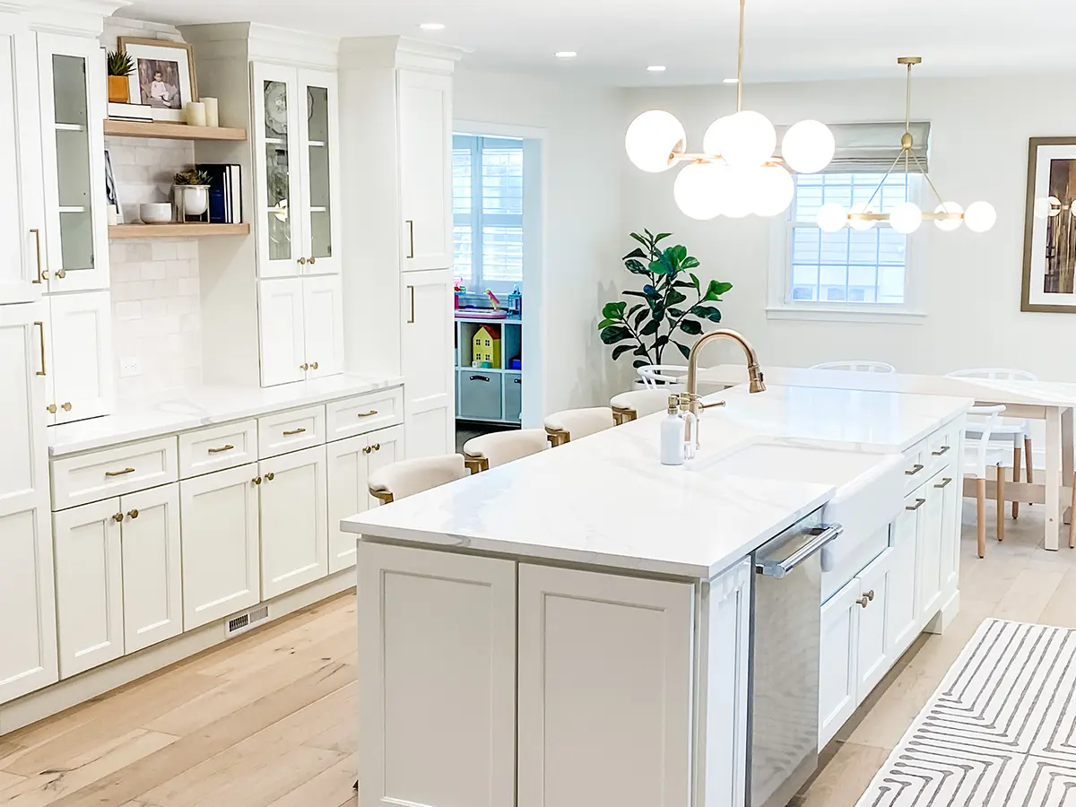 A large kitchen island with quartz counter and golden hardware on cabinets
