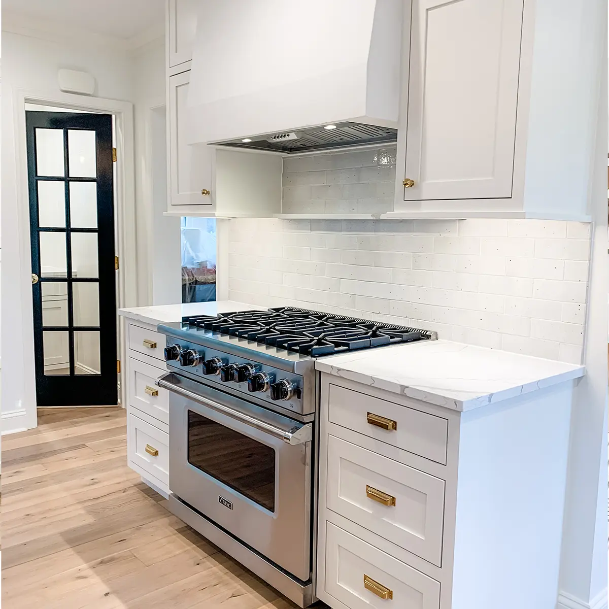 A kitchen range surrounded by cabinets with golden hardware