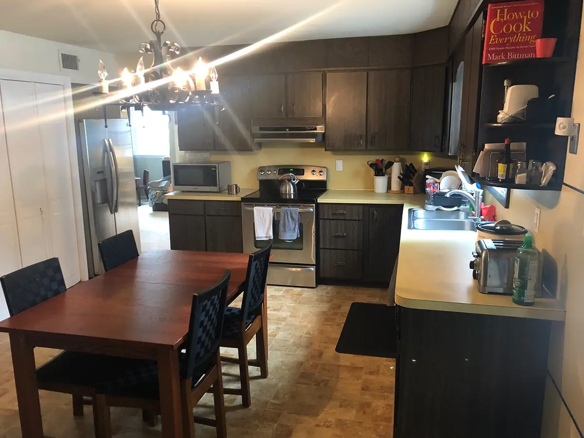 A dated kitchen with wood cabinets and a kitchen table with chairs