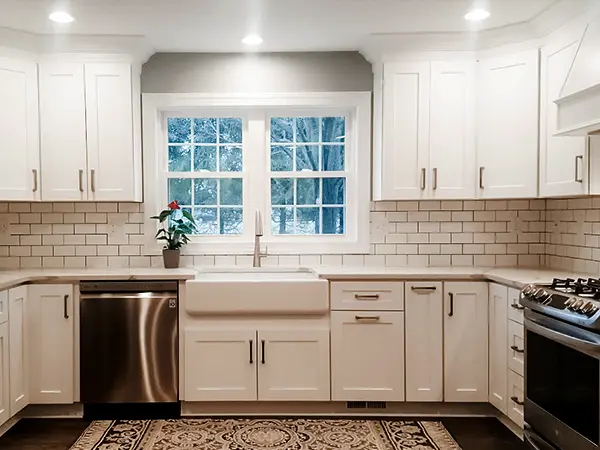 A bright kitchen with white cabinets and dark hardware