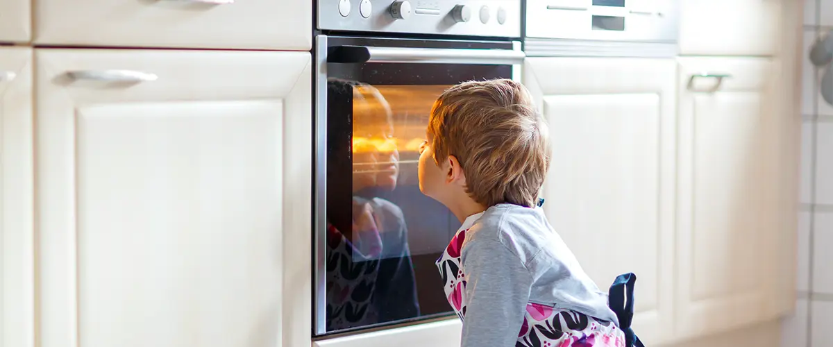 A kid in front of a kitchen range