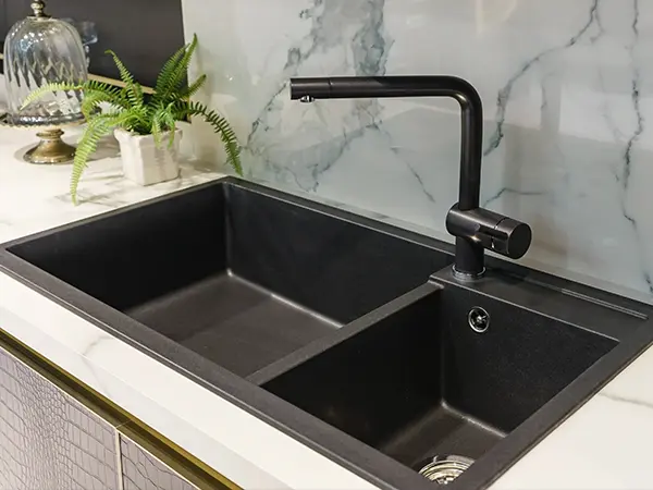 A black drop-in sink with a black faucet
