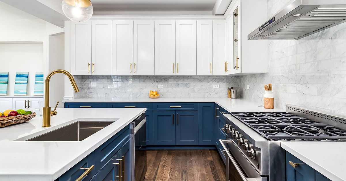 White upper cabinets with blue base cabinets and golden hardware