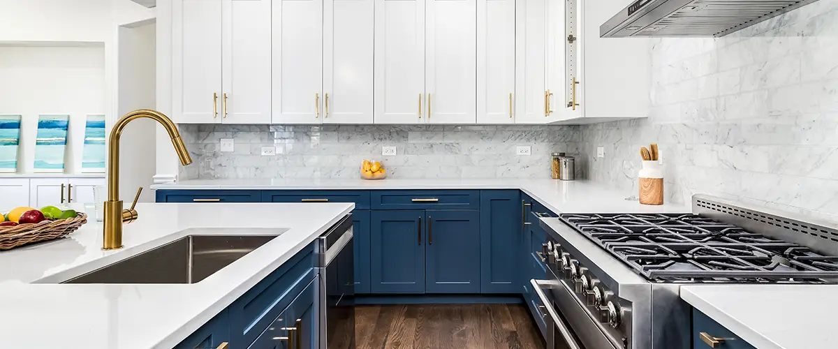 White upper cabinets with blue base cabinets and golden hardware