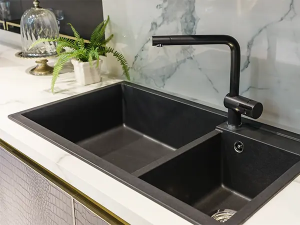 A black drop-in sink with a black faucet