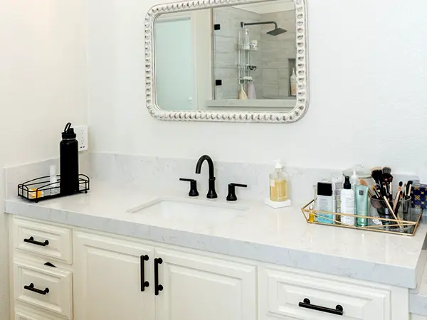 Bathroom remodeling with white vanity and cabinets and black fixtures.