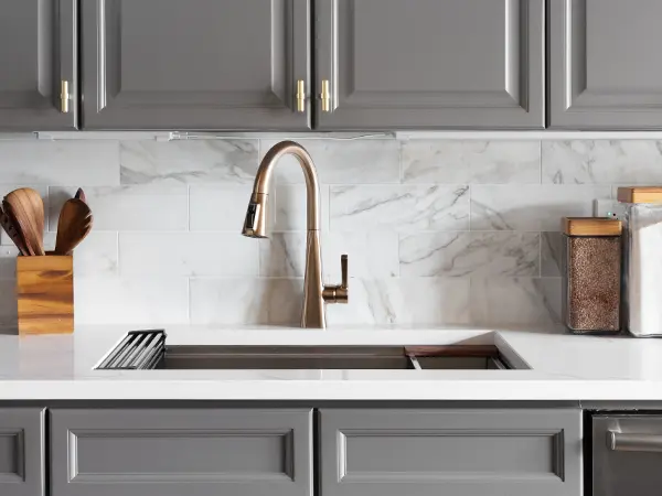 Gray kitchen cabinets with a golden faucet and undermount sink