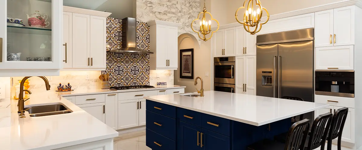 Dark blue island in a kitchen with white cabinets and golden hardware