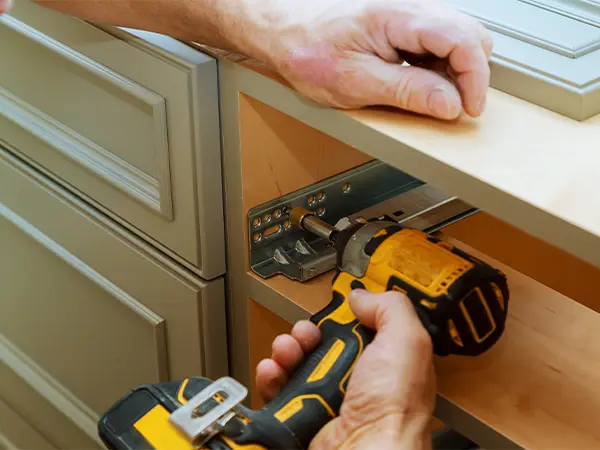 Updating kitchen cabinets using a screwdriver to install new cabinet hardware