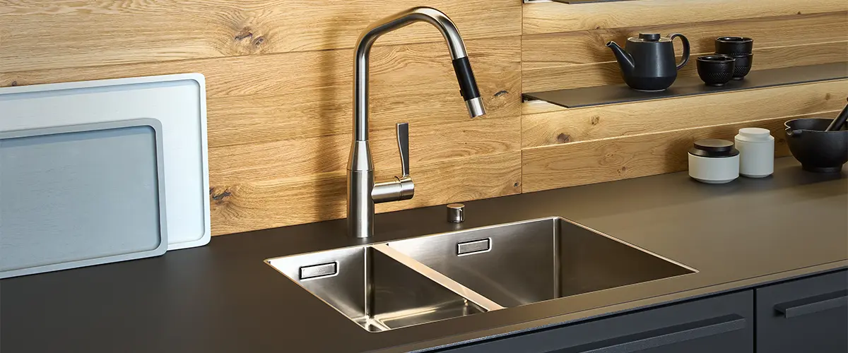 An undermount sink with an expensive faucet on a black countertop