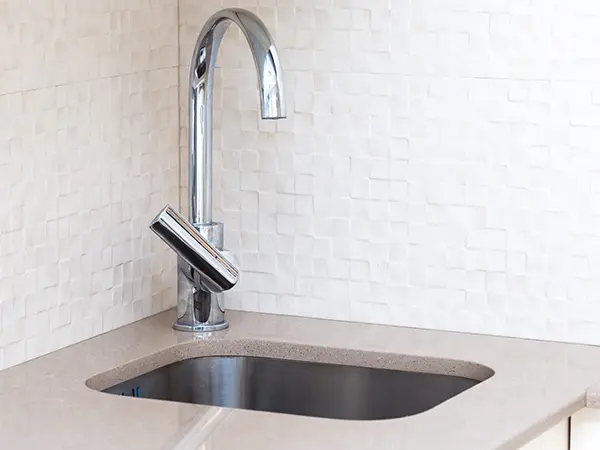 An undermount sink with stone countertop and silver faucet
