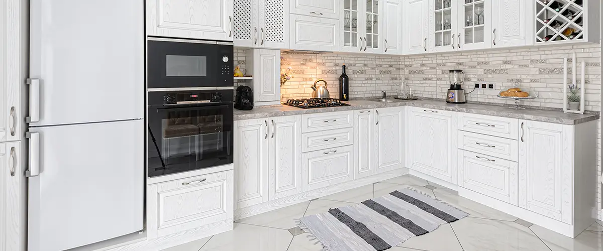 White kitchen cabinets, tile flooring, and expensive appliances