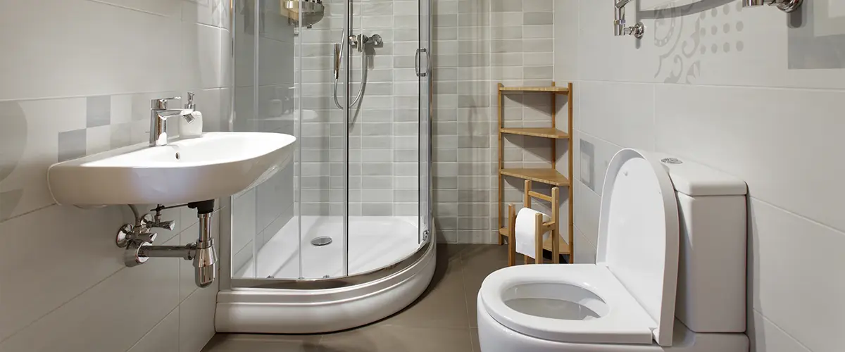An outdated bathroom with a glass shower with a pan