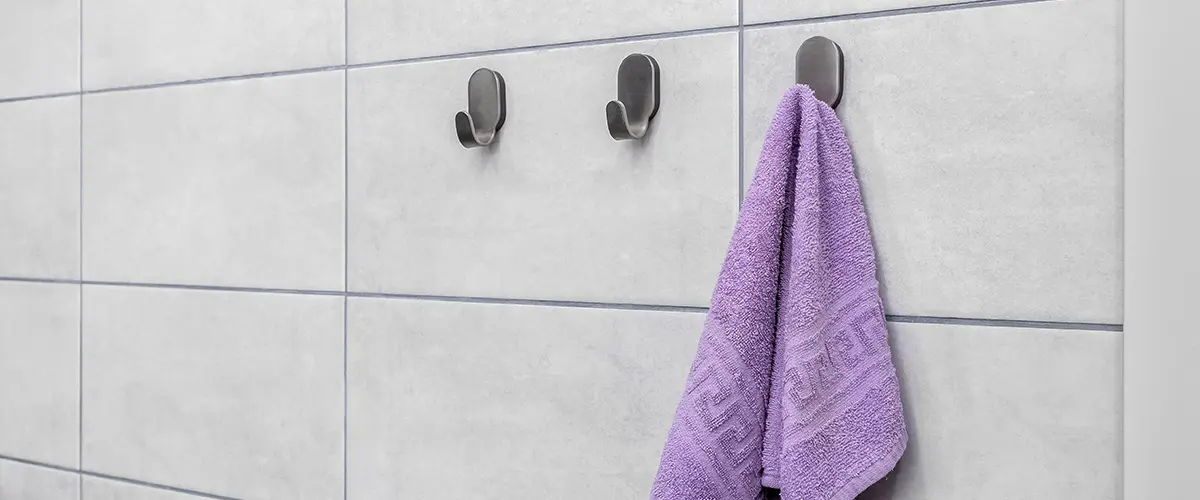 hanging hooks on a bathroom wall with a purple towel