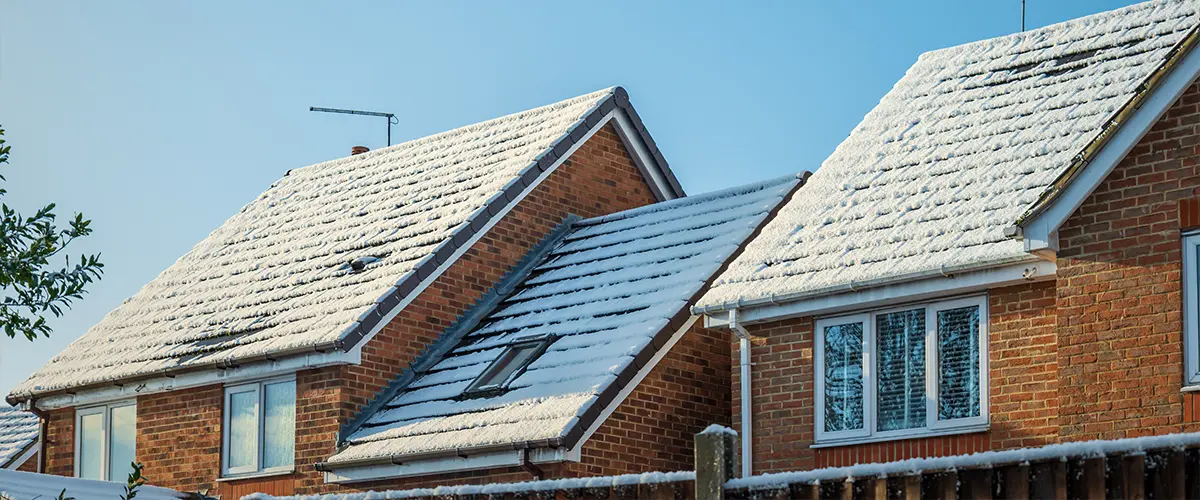 A brick house with snow on the roof