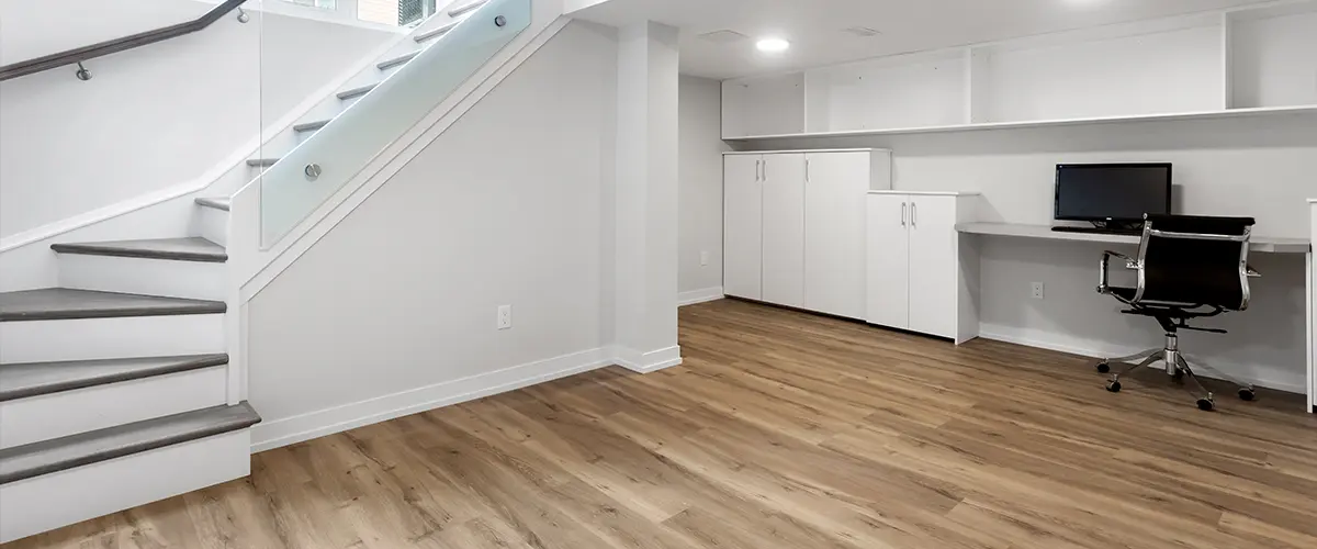 A basement addition with a computer and white cabinets