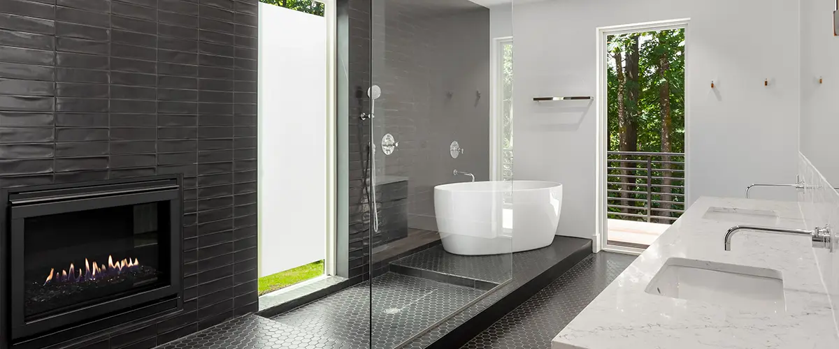 A walk in shower with a glass panel and black tile surround