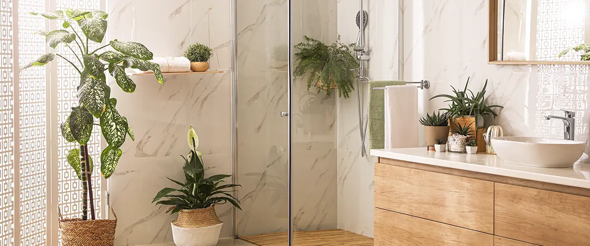 Framed walk-in shower with a lot of plants and wood vanity