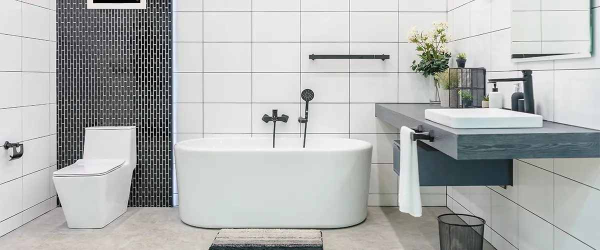 Freestanding tub with simple vanity and dark tile backsplash
