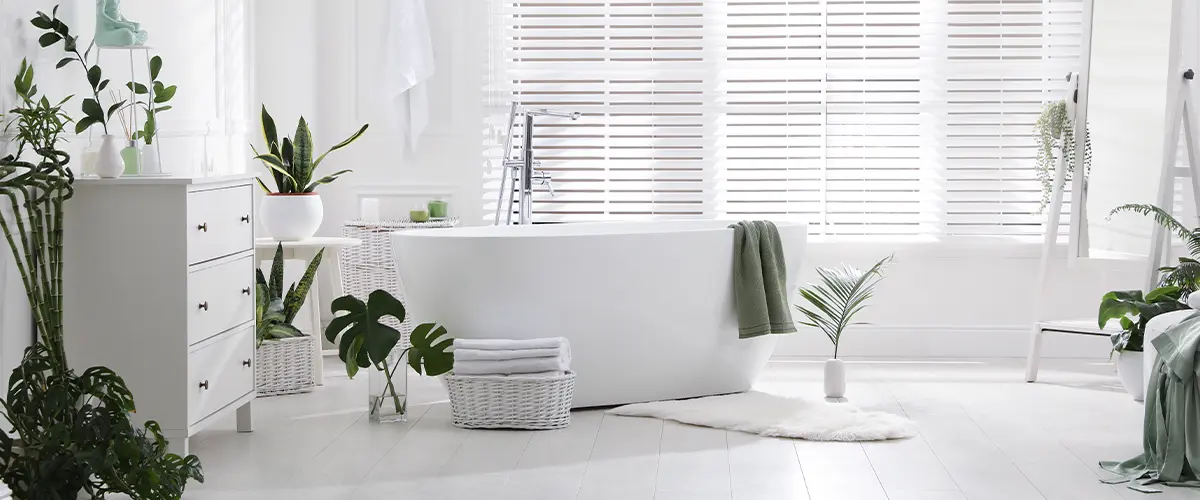 A beautiful white bathroom with plants and a freestanding tub