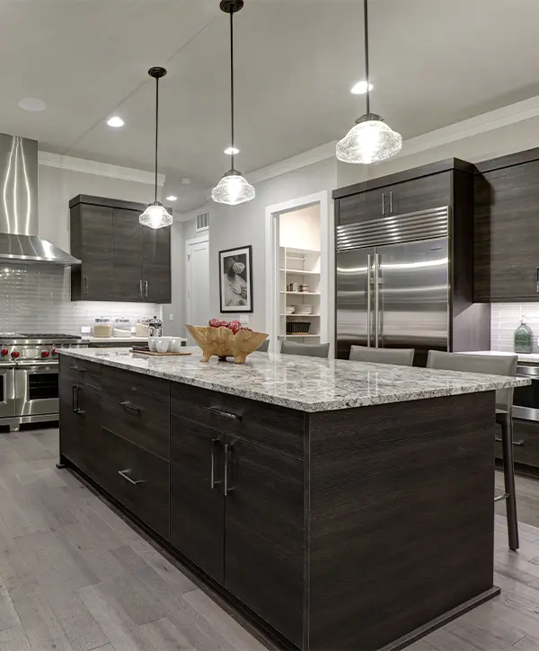 Black kitchen cabinets with overhang lights and wood flooring