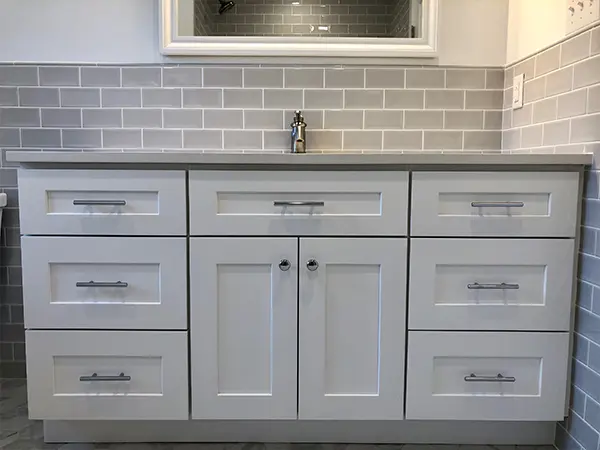 Gray vanity with tile backsplash and a white mirror