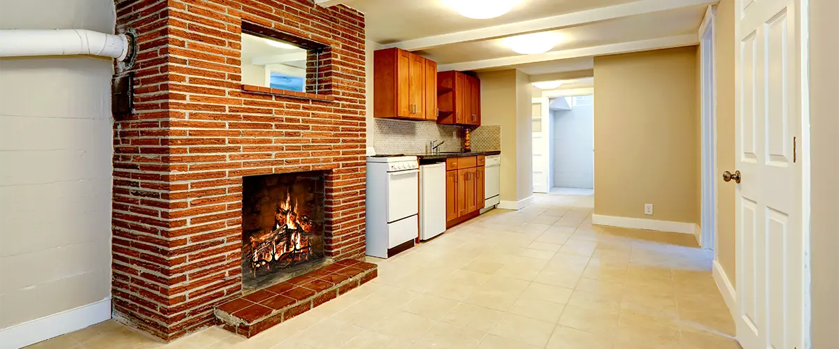 A basement remodeled with a brick chimney and dated cabinets