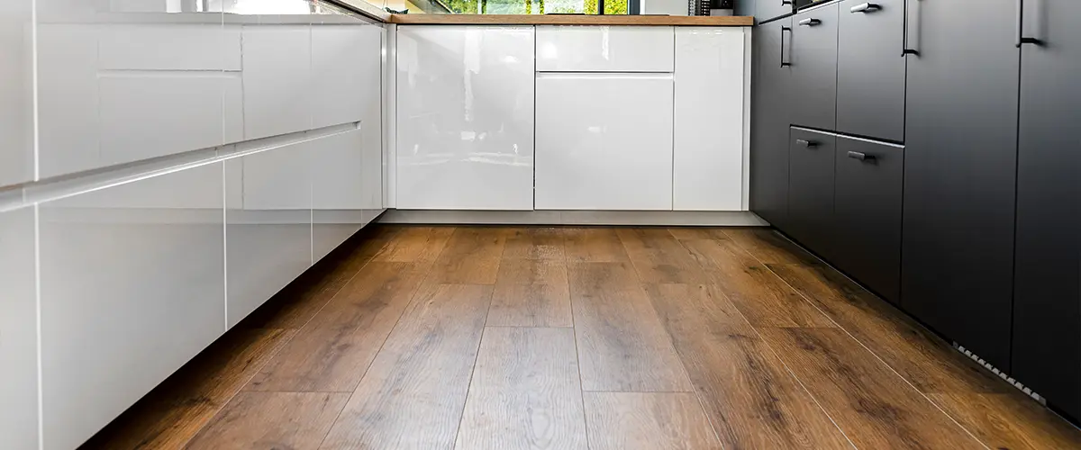 Laminate kitchen flooring material in a space with black and white modern cabinets