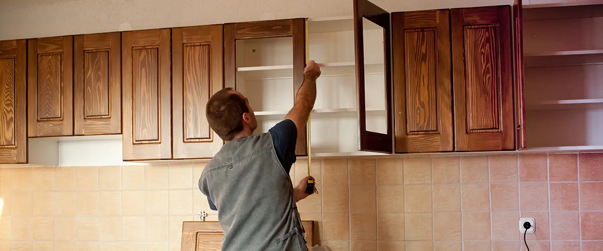 A contractor installing wood kitchen cabinets