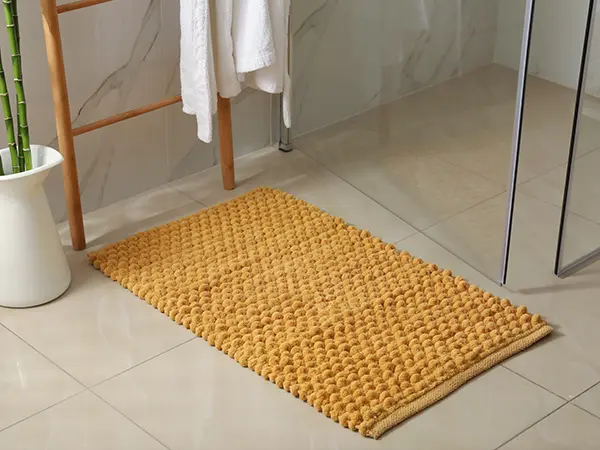 A tile floor in a bath with an orange matt