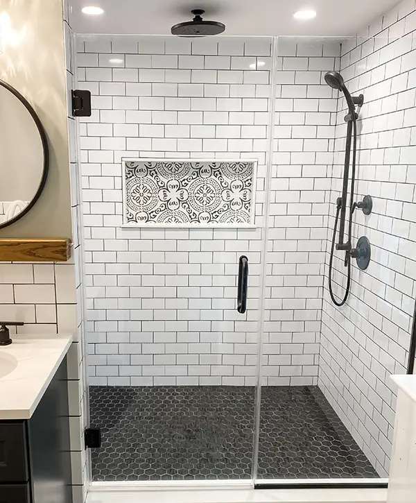 A tiled bathroom shower with black water fixtures
