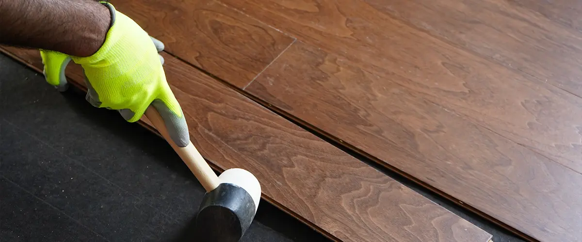 Hardwood floor installation process with a mallet