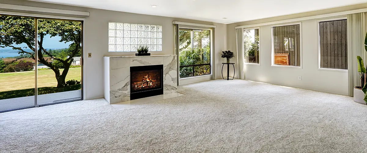 Walk-out basement with carpet flooring and a fireplace with marble slabs