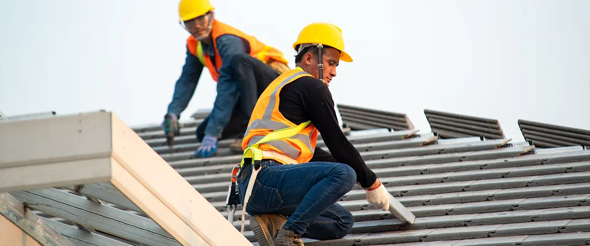 Workers on roof during Roofing Replacement In Springfield, PA, installing tiles.