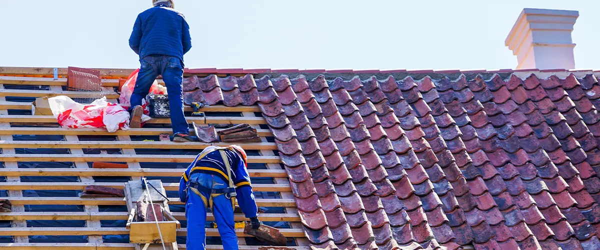 Workers on roof working on Roofing Replacement In Springfield, PA, installing tiles.