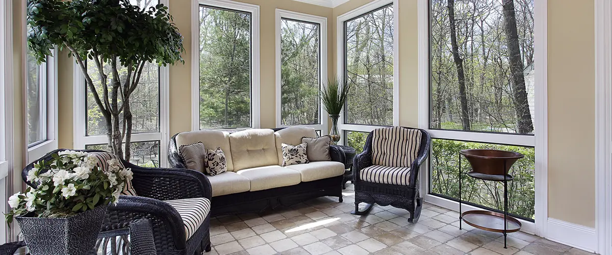 Bright sunroom home addition in berwyn with wicker furniture, large windows, and natural light, perfect for relaxing and enjoying outdoor views in a cozy setting.