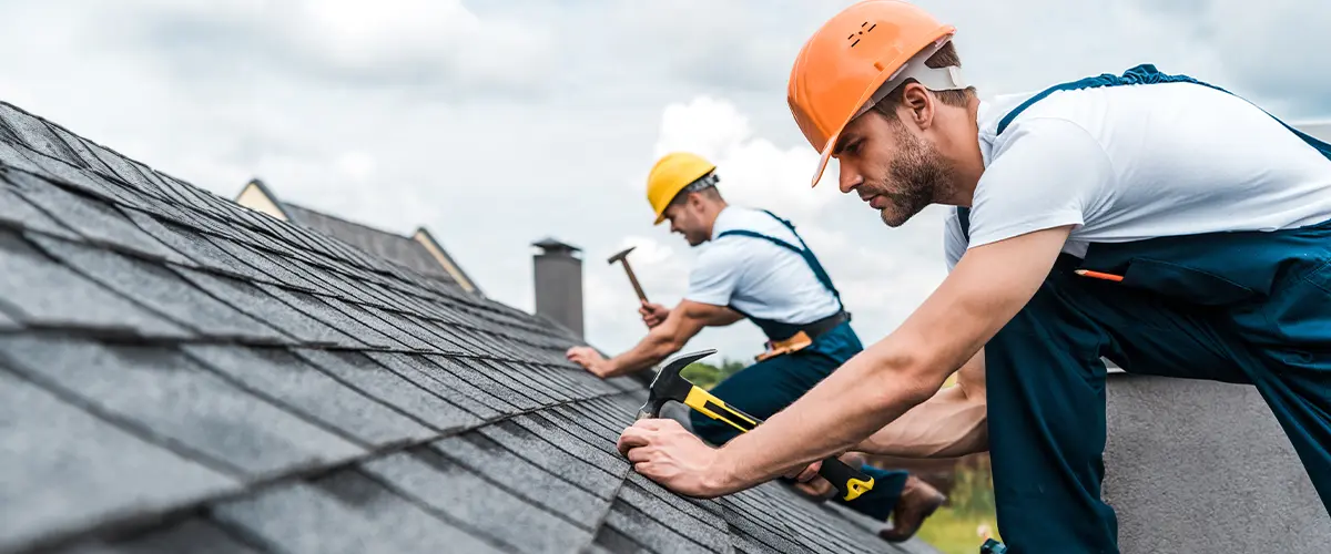 selective focus of handsome handyman installing roof with coworker in springfield