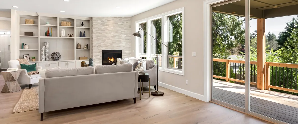 Modern living room interior with large windows, cozy seating, and a fireplace, showcasing a home remodeling project