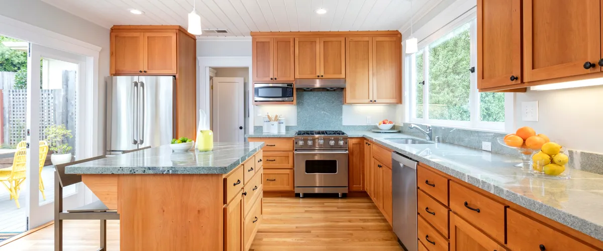 Modern wooden kitchen interior with a large center island, stainless steel appliances, and ample natural light