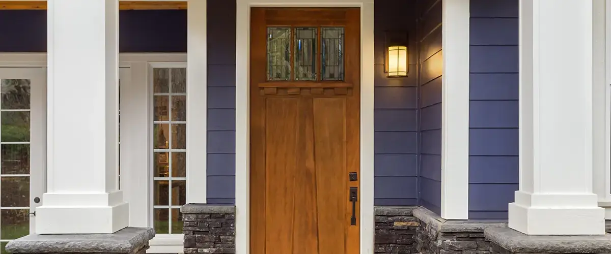 Wooden front door with decorative glass, set against a navy-blue house exterior