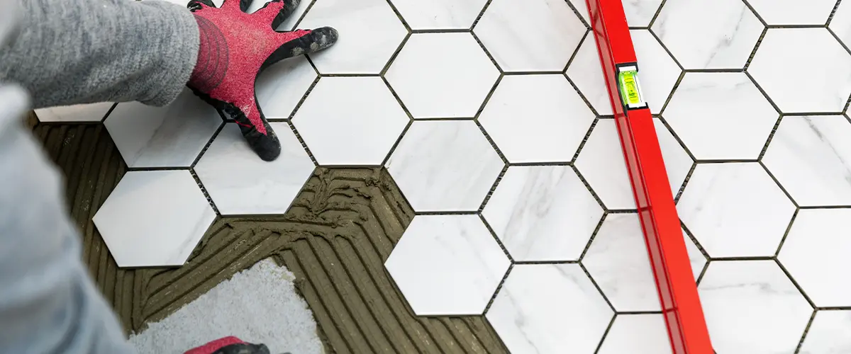 Installation of hexagonal marble tiles on a bathroom floor with precise leveling