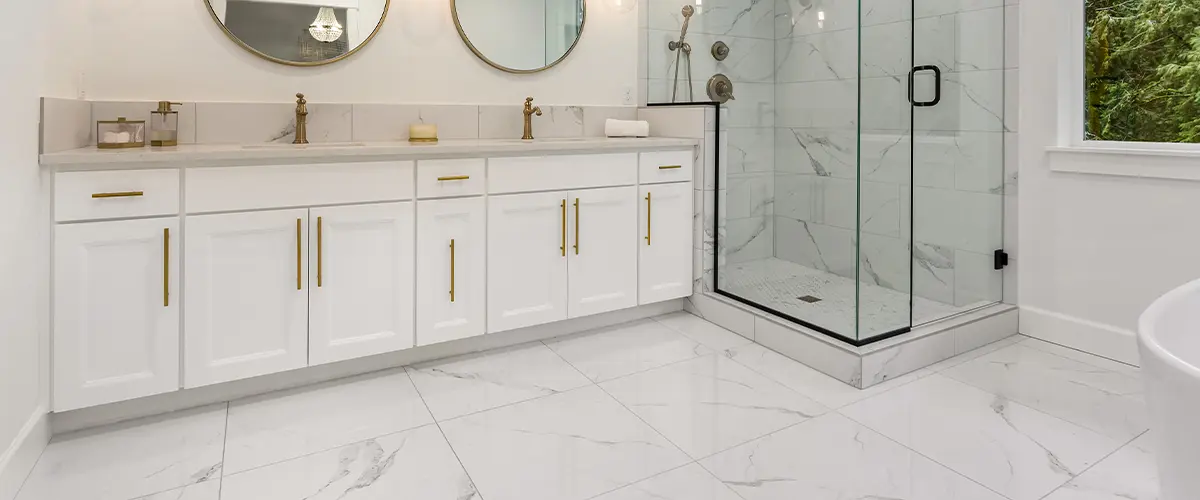 Modern bathroom with white cabinets, marble flooring, and glass shower enclosure