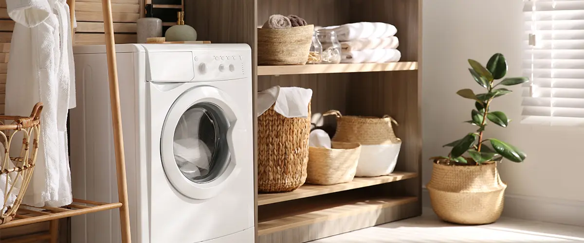 Modern laundry room featuring a washing machine, organized shelves, wicker baskets, and houseplants.