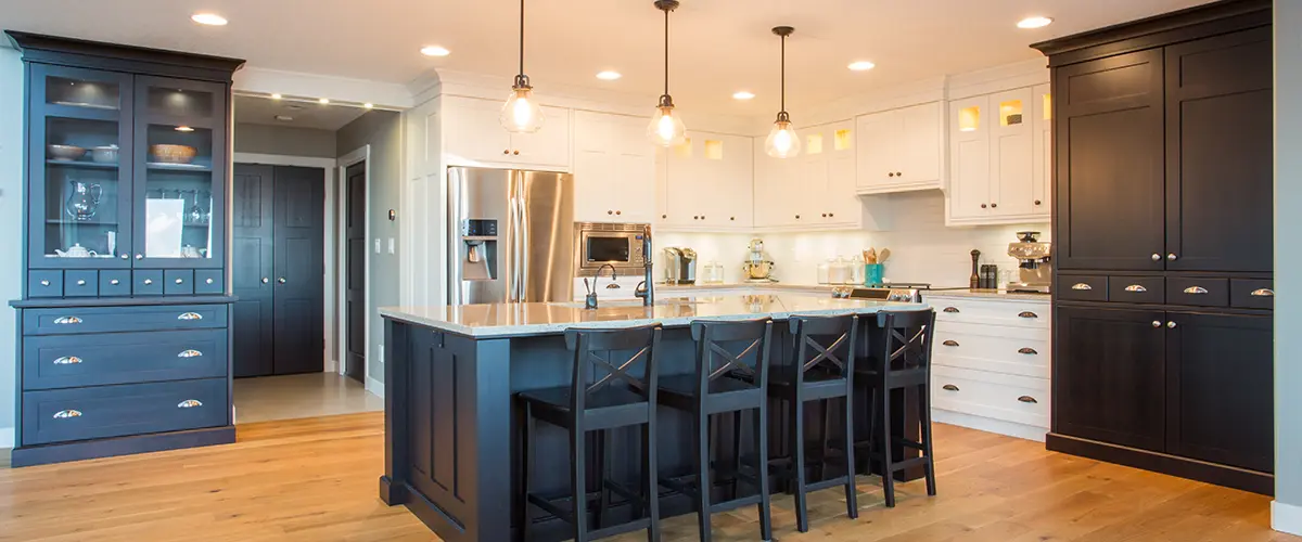 Spacious farmhouse-style kitchen with white and black cabinetry and wooden flooring.