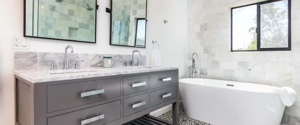 bright bathroom with marble accents, freestanding bathtub, and dual vanity