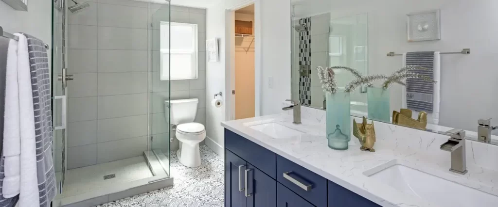 bright bathroom with patterned flooring, glass shower, and navy vanity